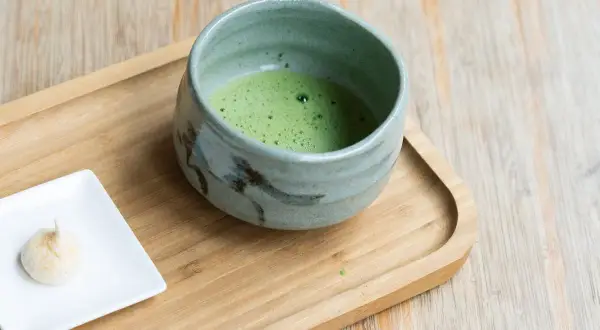 Zielone matcha w ceramicznej miseczce, obok małe bezy. Jak stosować keto matcha blue?