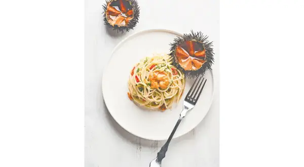 Spaghetti mit Seeigel-Soße und zwei ganze Seeigel. Entdecke, wie schmeckt Seeigel: eine delikate Meeresfrucht.