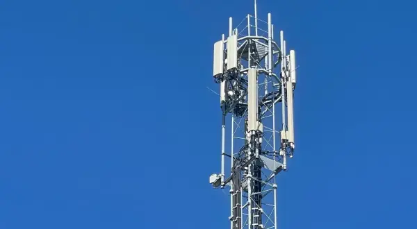 Wieża telekomunikacyjna z antenami LTE na tle błękitnego nieba.