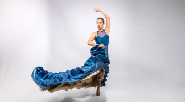 Bailarina con vestido azul ondeante, capturando la pasión y el arte de donde viene el flamenco.