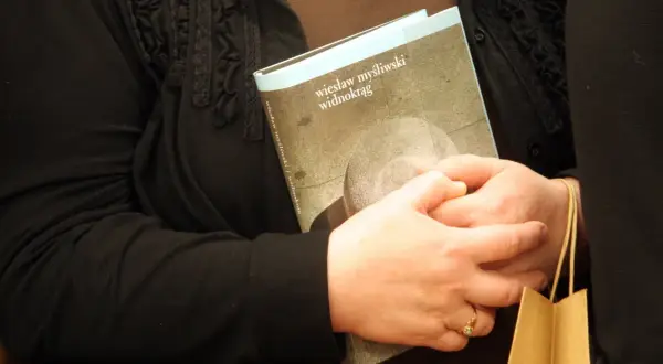 Dwie osoby trzymają książkę "Widnokrąg" Wiesława Myśliwskiego.