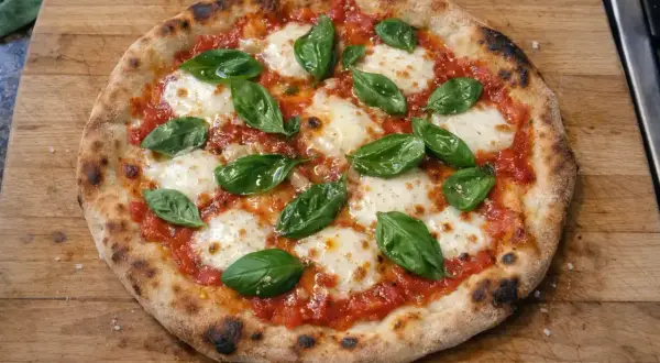 En hemmagjord pizza med tomatsås, mozzarella och färsk basilika. Ett perfekt pizza recept för en mysig kväll.