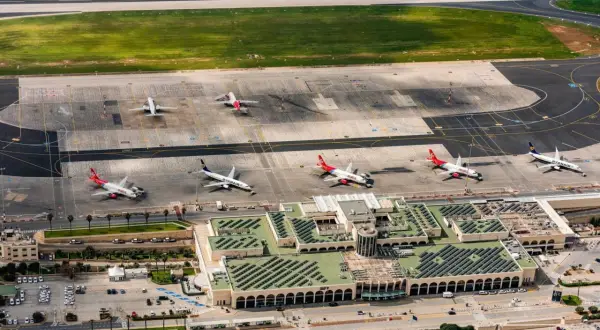 Lotnisko na Malcie, z samolotami Ryanair i Malta Air na płycie. Widok z lotu ptaka ukazuje ruchliwy terminal i pasy startowe.