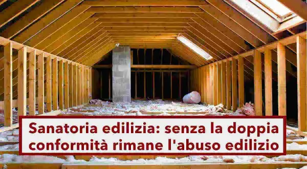 Sottotetto in costruzione, con travi in legno e isolamento. La scritta "Sanatoria edilizia: senza la doppia conformità rimane l'abuso edilizio" evidenzia un problema legale.