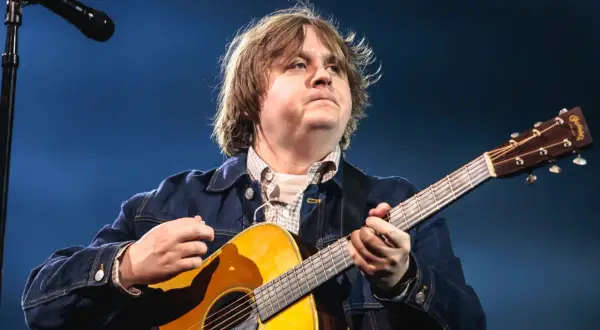 Lewis Capaldi gra na gitarze, mimo swojej choroby, z pasją i zaangażowaniem.