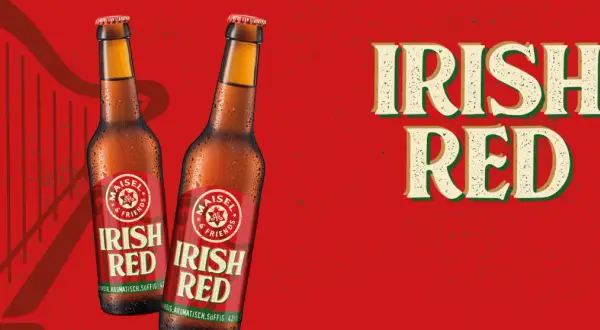 Zwei Flaschen "Irish Red" Bier vor rotem Hintergrund mit Harfenmotiv. Was ist Rotbier? Dieses Irish Red Ale ist vollmundig, aromatisch und süffig.
