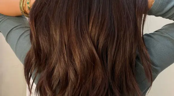 Cheveux bruns ondulés avec des reflets subtils. Une question se pose : comment enlever une patine cheveux pour retrouver une couleur naturelle ?