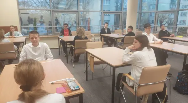 Uczniowie podczas mscdn konkursy przedmiotowe. Młodzi ludzie siedzą przy stołach, skupieni na zadaniach.