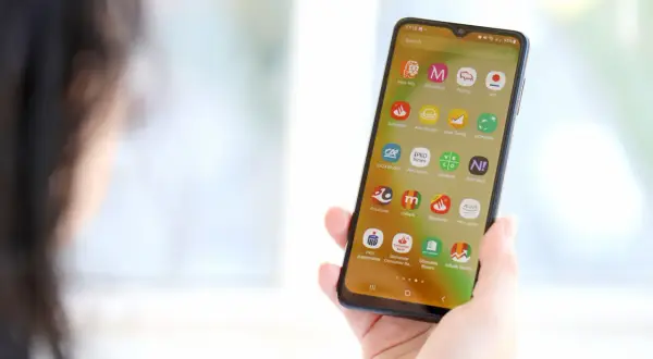 Dłoń trzyma smartfon z widocznymi ikonami aplikacji bankowych. Wśród nich jest mBank, co może być pomocne, gdy zastanawiasz się, jak zmienić numer telefonu w mBanku.