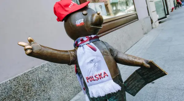 Pomnik misia z szalikiem "Polska" i czerwoną czapką, część szlaku łodzi bajkowej, pozdrawia przechodniów.