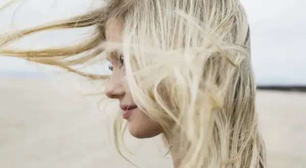 Profilo di una ragazza con lunghi capelli biondi mossi dal vento. Chissà se è il momento giusto quando tagliare i capelli luna.