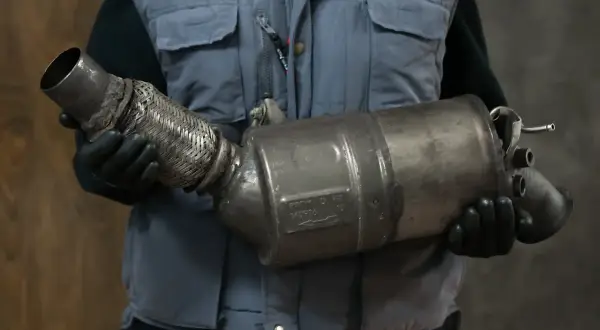 Mechanik w rękawiczkach trzyma zużyty DPF. Jak rozpoznać wypalanie DPF? To kluczowe dla sprawności silnika.