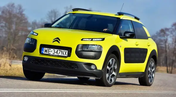 Żółty Citroen C4 Cactus na drodze. Kierowca testuje auto, zbierając pozytywne opinie o jego komforcie i oryginalnym wyglądzie.