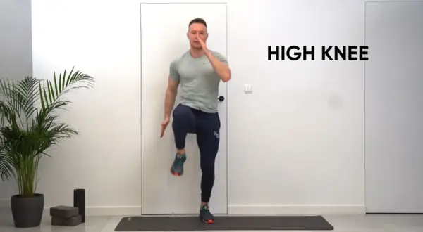 Mężczyzna wykonuje ćwiczenie high knees na macie treningowej.