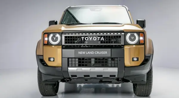 Złoty Toyota Land Cruiser 2020 z okrągłymi światłami i napisem "NEW LAND CRUISER" na grillu.