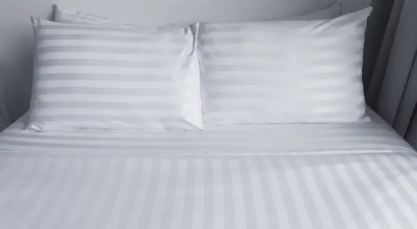 Biała pościel w prążki, przypominająca adamaszek. Co to za materiał? Miękki i elegancki, idealny do sypialni.