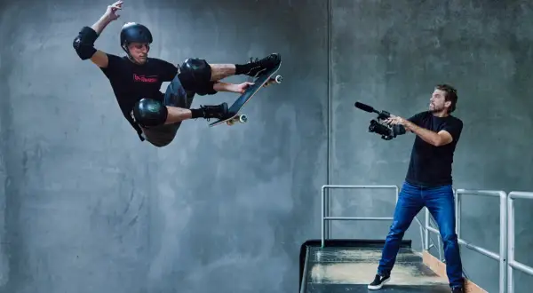 Tony Hawk w locie na deskorolce, filmowany przez operatora kamery.
