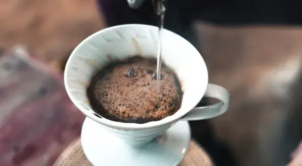 Gorąca woda powoli przelewa się przez mieloną kawę w dripperze, tworząc aromatyczną kawę po gruzińsku.