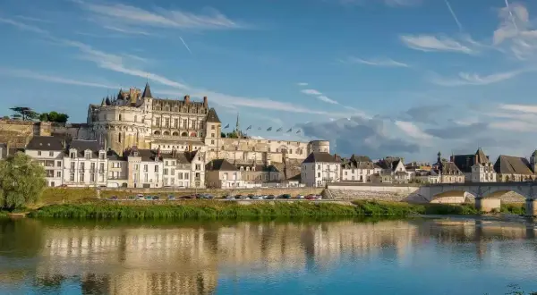 Le majestueux château d'Amboise se dresse fièrement au-dessus de la Loire, ses tours et façades blanches reflétant la lumière du soleil sur l'eau paisible.