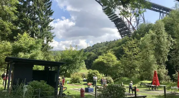 Familien genießen ein **adventure minigolf nrw** unter der imposanten Eisenbahnbrücke.