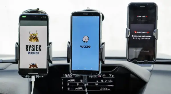 Trzy telefony w uchwytach na desce rozdzielczej: z lewej Rysiek, w środku Waze, a po prawej Yanosik. Którą nawigację wybierzesz?