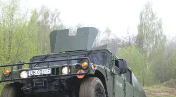Zielony humvee z tablicą rejestracyjną UB 00317 jedzie przez las.