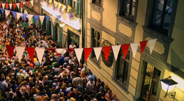 Buntes Treiben beim Bamberger Volksfest. Girlanden schmücken die Gasse, Menschenmassen feiern ausgelassen.