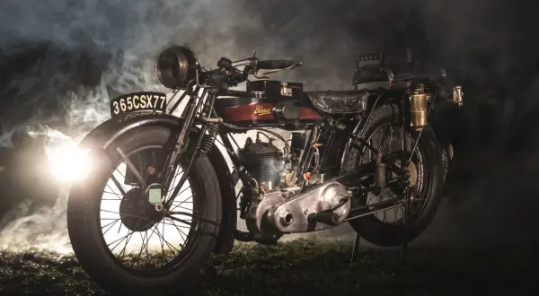 Stary motocykl z widocznym silnikiem i tablicą rejestracyjną. W tle mgła i światło, sugerujące tajemniczą atmosferę, która podkreśla jego historię i różne pojemności motocykli.