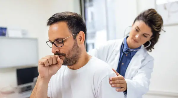 Médica examina a un hombre con tos, uno de los bronquitis síntomas.