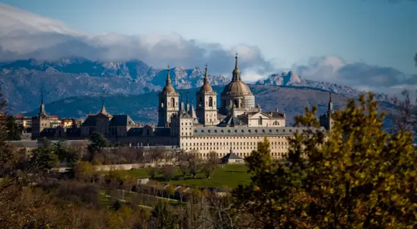 Impresionante Monasterio de El Escorial, un lugar clave que ver en la Comunidad de Madrid, con montañas nevadas al fondo.