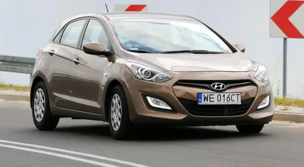 Brązowy Hyundai i30 2015 na drodze, z tablicą rejestracyjną WE 016CT.
