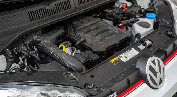 Silnik 1.0 TSI 110 KM w samochodzie Volkswagen. Widoczny akumulator, przewody i elementy osłony silnika.