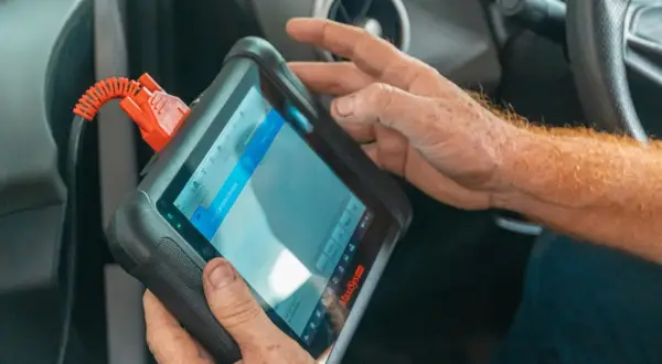 Mechanik używa podręcznego komputera diagnostycznego w samochodzie.