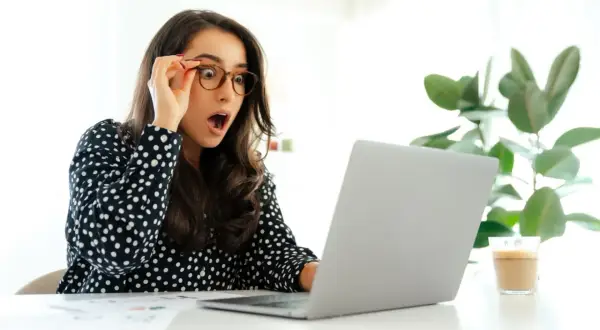 Zaskoczona kobieta odkrywa, ile dni urlopu można przenieść na następny rok, patrząc na ekran laptopa.