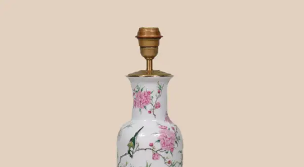 Een lamp maken van vaas: een witte vaas met roze bloemen en een vogel, omgebouwd tot lamp met een gouden fitting.