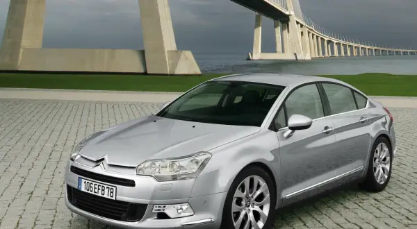 Srebrny Citroen C5 na tle mostu. Wiele osób chwali ten model, a opinie o Citroen C5 są zazwyczaj pozytywne.