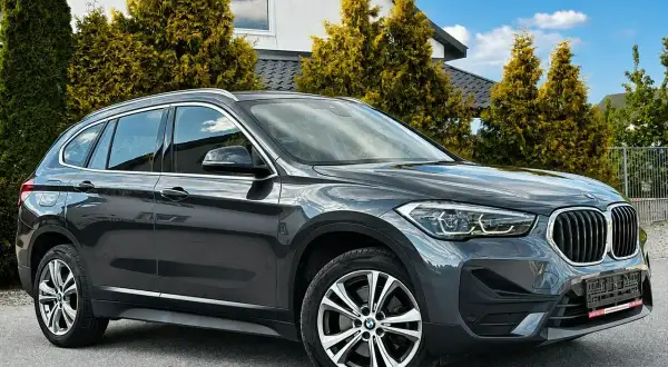 Elegancki, ciemnoszary BMW X1 na tle nowoczesnego domu. Sprawdź atrakcyjną bmw x1 cena!