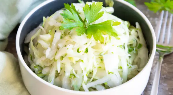 Frischer Krautsalat, perfekt zum krautsalat selber machen. Mit Petersilie garniert, serviert in einer Schüssel.