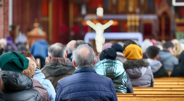 21 kwietnia. Ludzie siedzą w kościele, patrząc w stronę ołtarza z krzyżem.
