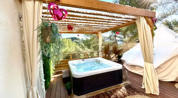 Jacuzzi extérieur sous pergola, décoré de cœurs, près d'une yourte dans les Alpes-Maritimes. Détente et nature.