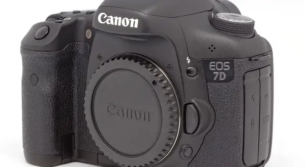 Czarny aparat Canon EOS 7D z obiektywem na białym tle.