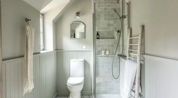 Douche, WC et lavabo dans une petite salle de bain 3m2. Un style épuré et fonctionnel avec des carreaux gris et un mur lambrissé.