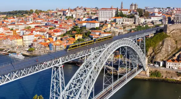 Most zwodzony w Porto z żółtym tramwajem, widok na miasto i rzekę. Szukasz informacji o wino porto cena?