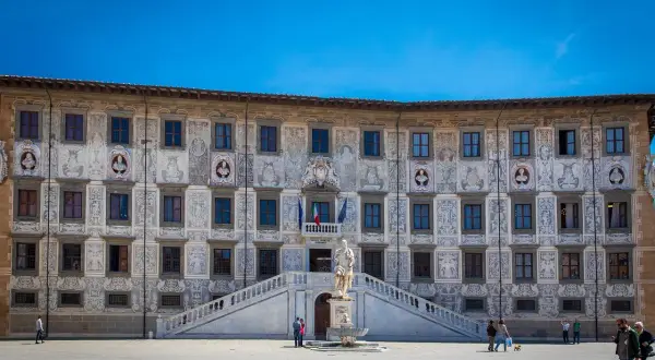 Piazza dei Cavalieri a Pisa: un palazzo storico con affreschi, una statua e una fontana. Cosa vedere a Pisa? Questo è un must!
