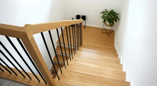 Nowe schody drewniane z czarnymi balustradami. Zobacz, jak zrobić schody drewniane, by nadać domowi ciepły i nowoczesny wygląd.