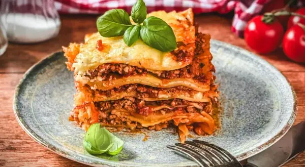 Ein Stück Lasagne mit Hackfleisch, belegt mit frischem Basilikum. Ein köstliches lasagne rezept mit hackfleisch.