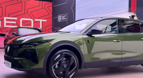 Nowy Peugeot 408 Hybrid w kolorze oliwkowym prezentuje się nowocześnie. Z przodu widoczny jest charakterystyczny grill i reflektory.