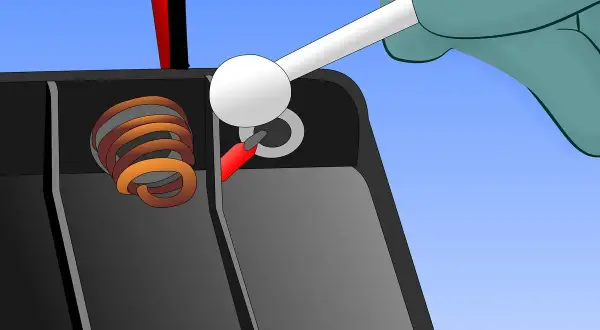 Mit einem Wattestäbchen wird die Korrosion an den Batteriepolen entfernt, um eine ausgelaufene Batterie zu reinigen.