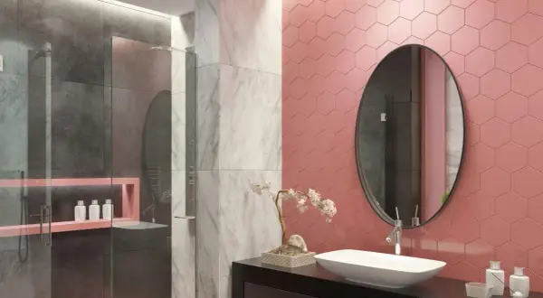 Bagno moderno con doccia, dove le piastrelle rosa a nido d'ape contrastano con il grigio e il marmo.