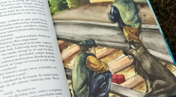 Opis psa Lampo: pies siedzi obok mężczyzny na dachu, czujnie obserwując otoczenie.